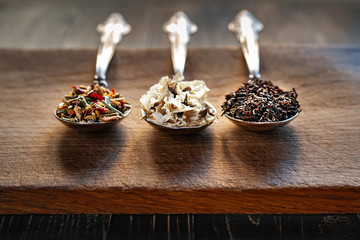 Various types of dry tea leaves and jasmine. The composition of tea with different types of tea from different herbs. Tea leaves and jasmine flowers on wooden background.