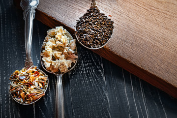 Various types of dry tea leaves and jasmine. The composition of tea with different types of tea from different herbs. Tea leaves and jasmine flowers on wooden background.