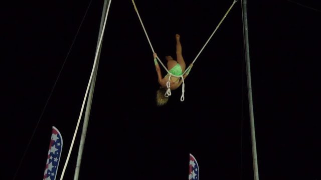 Young girl is an acrobat on a high swing