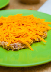 Close Up of Shredded Cheddar Cheese on Top of Middle Eastern Hummus on a Green Plate