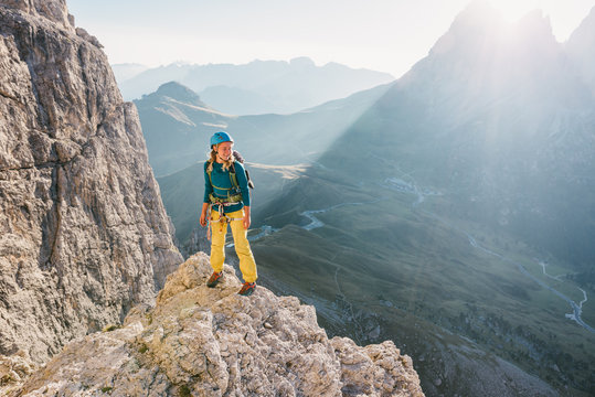 Female alpinist standing on high mountain peak in the sunset 