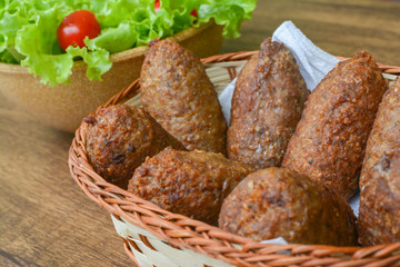 kibe - delicious brazilian salty on wooden table and accompanied by lemons and lettuce salad with tomatoes