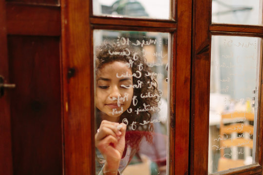 Young woman writing on glass of shop
