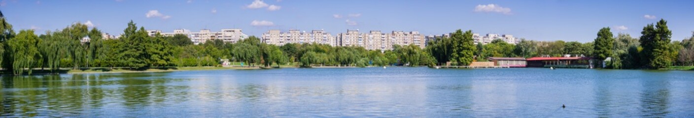 Fototapeta na wymiar Lake in Tineretului Park surrounded by residential buildings, near downtown Bucharest, Romania