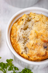 Polenta with mushrooms in white ramekin bowl on wooden rustic table. Close up