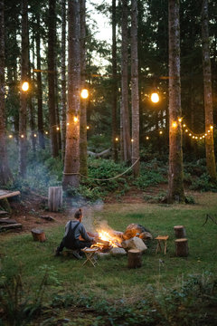 a man tends a campfire in the forest  