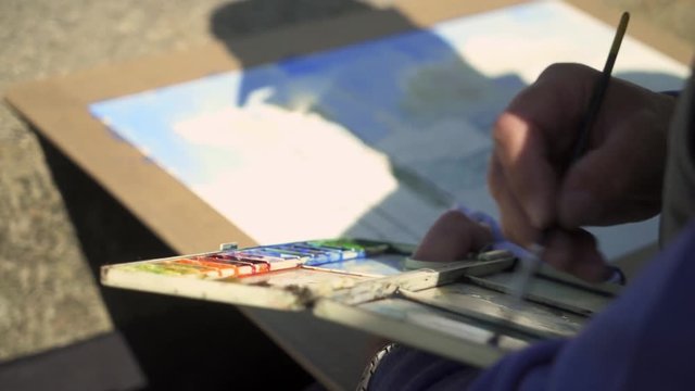 Close-Up of the Painting process of the aquarel picture on painters table on the street