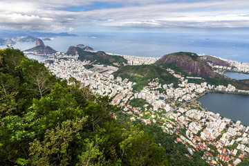 Fototapeta na wymiar Views from Christ The Redeem mountain over the Rio do Janeiro city, suburbs and favelas, amazing views over the bays, islands, beach and the city skyline from the top on a cloudy day, Brazil 