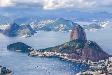 Naklejka premium Views from Christ The Redeem mountain over Sugar Loaf, Rio do Janeiro city, suburbs and favelas, amazing views over the bays, islands, beach and the city skyline from the top on a cloudy day, Brazil 