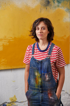 Female Painter With Hands In Pockets Against Painting At Studio