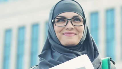 Excited Muslim woman holding tutorial books, gender equality in education