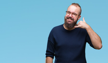 Young caucasian hipster man wearing sunglasses over isolated background smiling doing phone gesture with hand and fingers like talking on the telephone. Communicating concepts. - obrazy, fototapety, plakaty