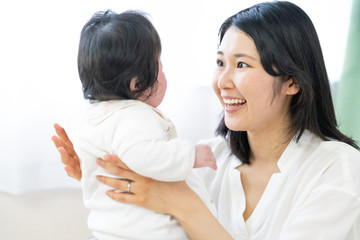 portrait of young asian mother and baby relaxing in living room