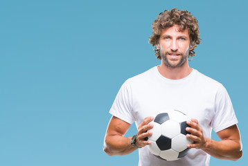 Handsome hispanic man model holding soccer football ball over isolated background with a happy face standing and smiling with a confident smile showing teeth