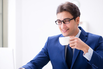 Young handsome businessman drinking coffee in the office 