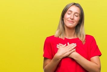 Young beautiful woman over isolated background smiling with hands on chest with closed eyes and grateful gesture on face. Health concept.