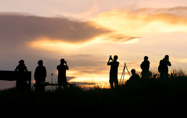 silhouette of traveler taking picture of landscape during sunrise.
