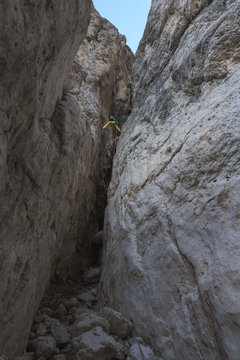 Skilled female alpinist rappelling in between two rock walls
