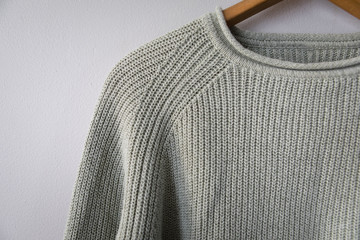 Light green sweater hanging on grey wall