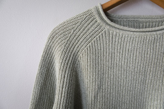 Light green sweater hanging on grey wall