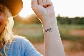 Woman with ""worthy"" tattooed on her arm