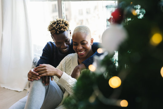 Young multiethnic couple celebrating Christmas at home. 