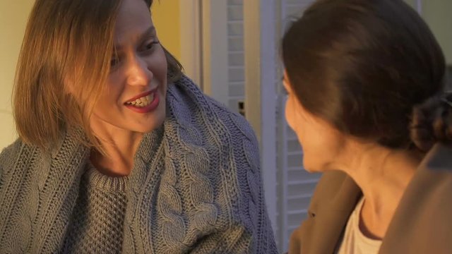 Women holding hands and talking, confidential conversation in cozy evening