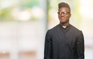 Naklejka premium Young african american priest man over isolated background smiling looking side and staring away thinking.