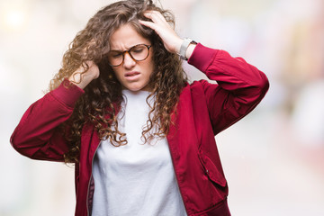 Beautiful brunette curly hair young girl wearing jacket and glasses over isolated background with hand on head for pain in head because stress. Suffering migraine.