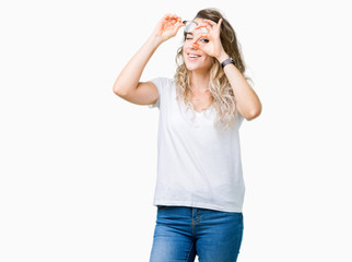 Beautiful young blonde woman wearing glasses over isolated background doing ok gesture with hand smiling, eye looking through fingers with happy face.
