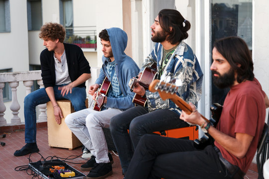 young people playing music together on a terrrace on a rooftop at sunset