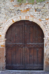 Fototapeta na wymiar Barolo, Italy 04-10-2011 Rustic wood door in a brick arch in Barolo, in the Piemonte wine region of northern Italy.