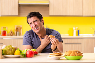 Man having hard choice between healthy and unhealthy food