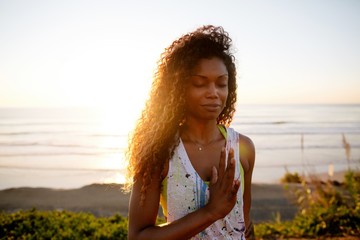 Fit, stylish woman practicing yoga at sunset on grass