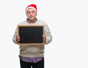 Handsome senior man wearing christmas hat and holding blackboard over isolated background with a...