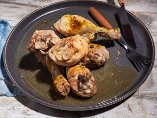 Chicken drumsticks cooked in the microwave on a gray round plate, denim blue napkin, cutlery.