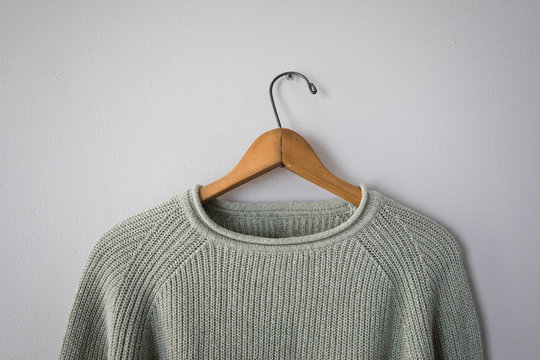 Light green sweater hanging on grey wall