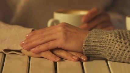 Female friends holding hands on table, concept of support and trustful relations