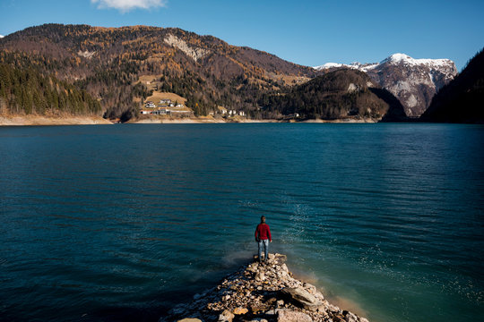 Man walking down a cliff along a lake on mountains