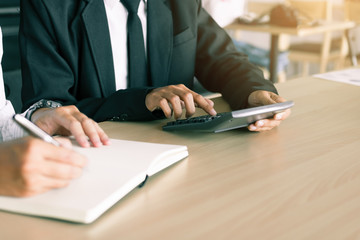 Salesman pressing calculator and customer writing make note report on notebook.