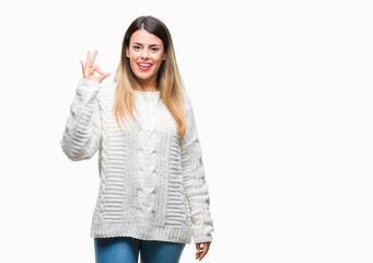 Obraz premium Young beautiful woman casual white sweater over isolated background smiling positive doing ok sign with hand and fingers. Successful expression.