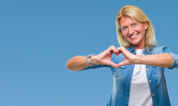 Middle age blonde woman over isolated background smiling in love showing heart symbol and shape with hands. Romantic concept.
