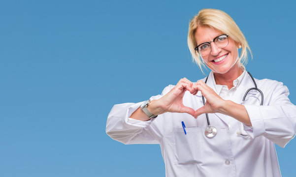 Middle age blonde doctor woman over isolated background smiling in love showing heart symbol and shape with hands. Romantic concept.