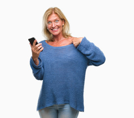 Middle age blonde woman sending message using smartphone over isolated background with surprise face pointing finger to himself
