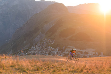 Male biker riding downhill mountain singletrack in the golden hour
