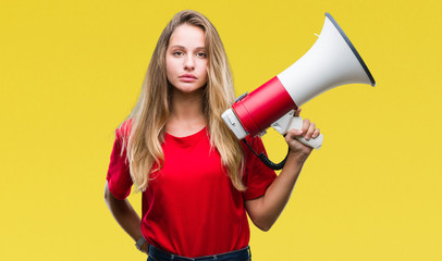 Young beautiful blonde woman yelling through megaphone over isolated background with a confident expression on smart face thinking serious