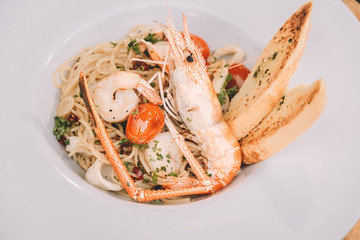 spaghetti pasta with shrimps and sweet basil on white plate over wooden table