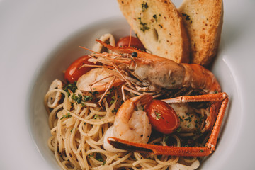 spaghetti pasta with shrimps and sweet basil on white plate over wooden table