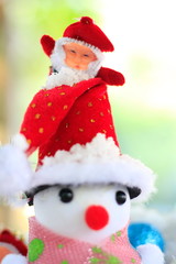 Snow man with a Christmas ornament on a snow background blur.