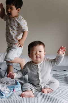 Baby and little kid playing on bed